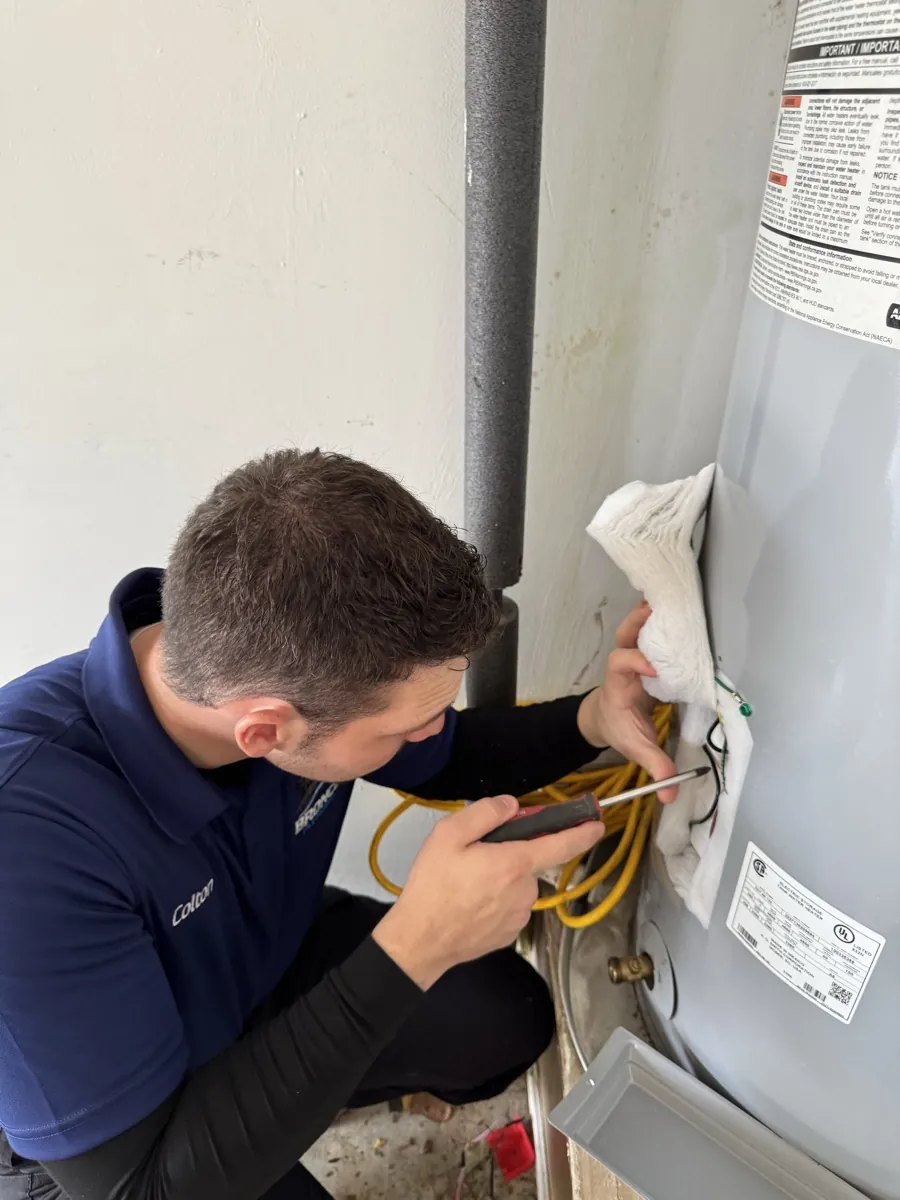 Colton Staley inspecting a water heater connection for Bronco Plumbing in DFW
